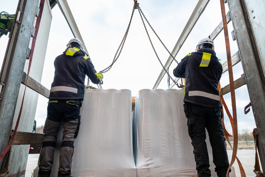 Workers using chain rigging to lift heavy materials in industrial lifting operation