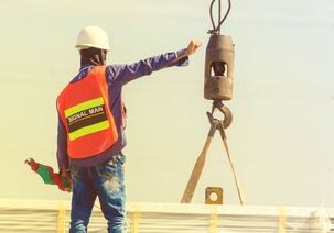 A man in an orange vest holding onto a crane hook